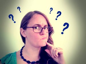 Eine Frau, die fragend schaut. Neben ihrem Kopf Fragezeichen. Wie antwortet man nur auf fiese Fragen?