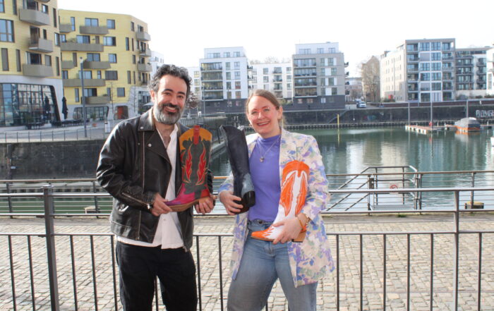 Marietta Gädeke und Hassan Eisso halten Stiefel der Marke Ms Sucra